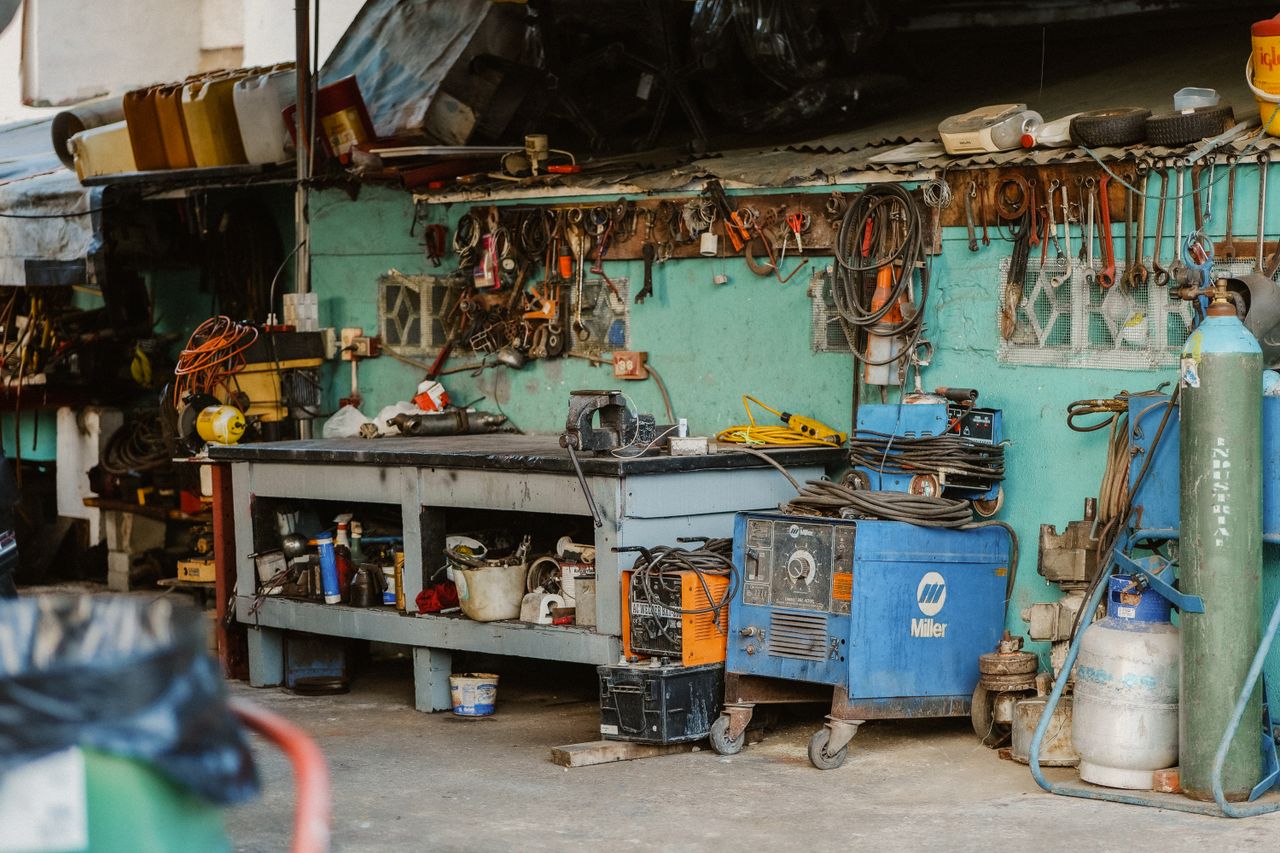 who-we-are A cluttered workshop with tools, welding equipment, and storage solutions.