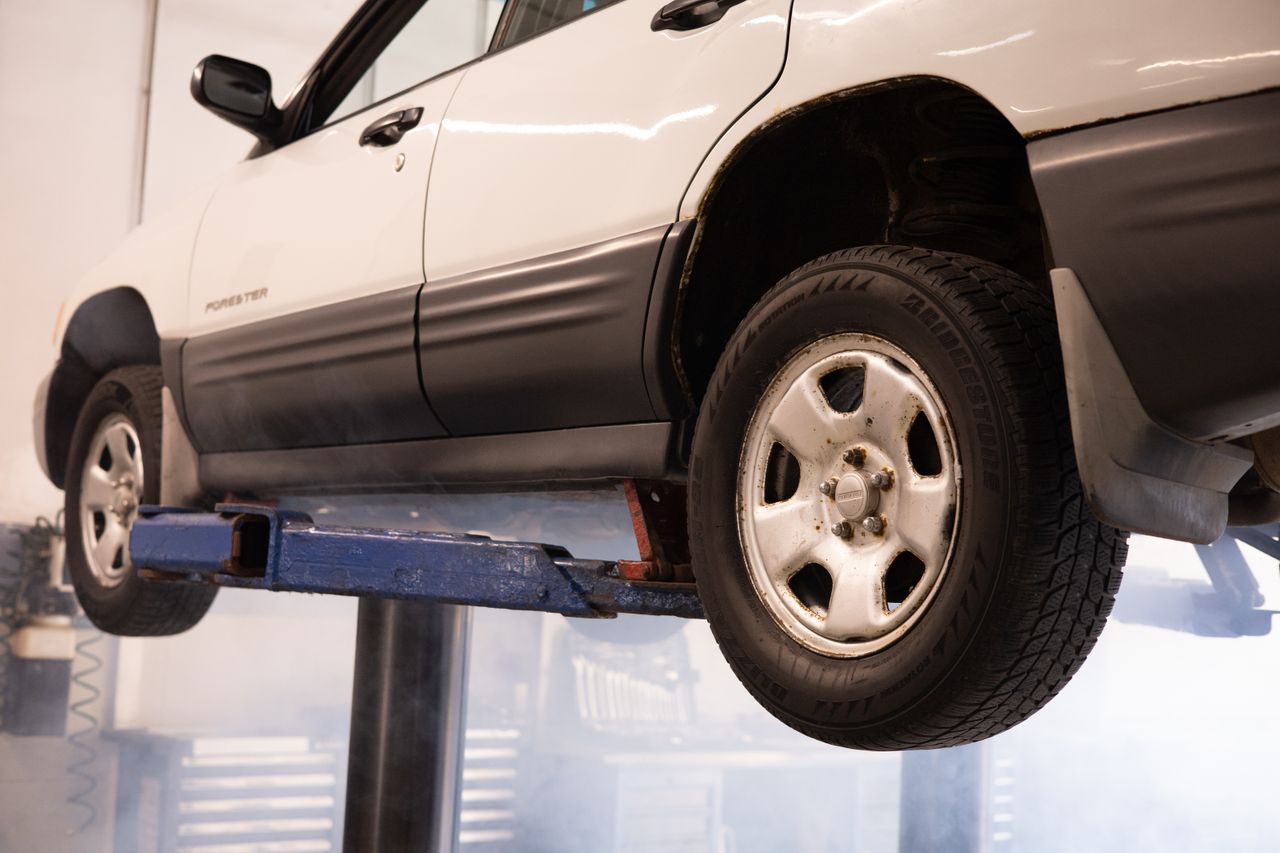 journey A white car suspended on a lift in an automotive repair shop, showcasing maintenance work.