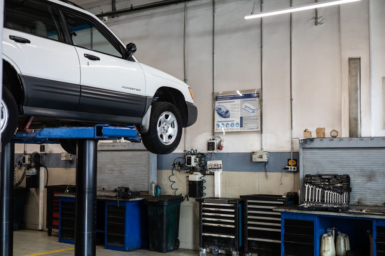 A car is elevated on a lift in a modern automotive repair shop, showcasing tools and equipment.